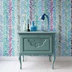 a blue nightstand sitting next to a colorful wallpaper