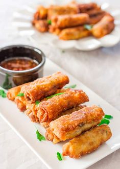 some food is sitting on a white plate with dipping sauce in the bowl next to it