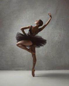 a young ballerina in a black leotard and tutu is posing for the camera