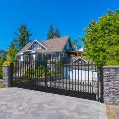 an iron gate in front of a house with stone walls and brick walkway leading up to it