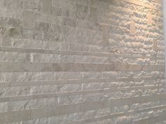 a bathroom with a white tiled wall next to a toilet and shower head mounted on the wall