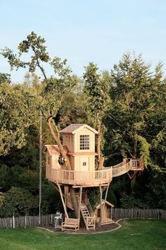 a tree house built into the side of a lush green field with trees in the background