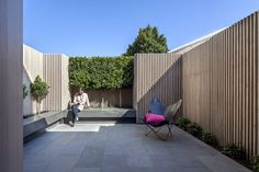 a person sitting on a bench in the middle of an outdoor area with wooden slats