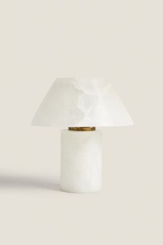 a white table lamp sitting on top of a white floor next to a light bulb