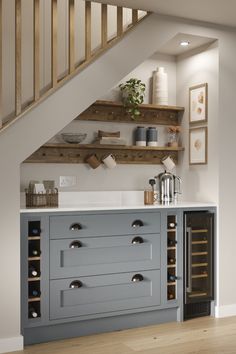 a kitchen under the stairs with wine racks