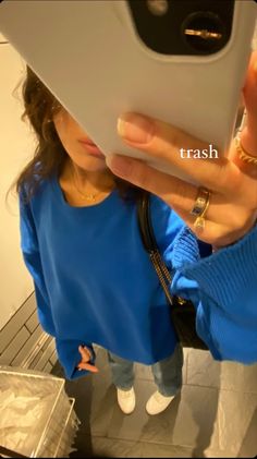 a woman taking a selfie with her cell phone in front of her face and wearing a blue sweater