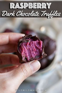 a hand holding a half eaten chocolate covered in raspberry frosting on top of a plate