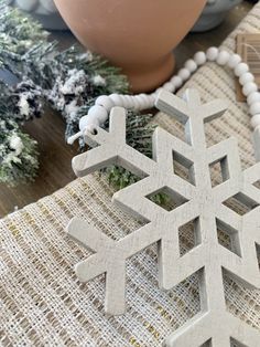 a snowflake ornament sitting on top of a table next to a potted plant