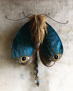 a blue butterfly with gold eyes hanging on a wall