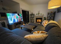 a living room filled with furniture and a flat screen tv mounted on the wall next to a fire place