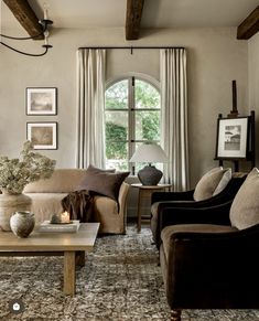 a living room with couches, chairs and pictures hanging on the wall above them