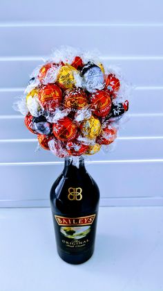 a bottle filled with assorted candies on top of a white table next to a wall