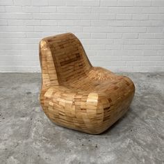 a wooden chair sitting in front of a white brick wall on concrete floored area