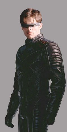 a man in a black leather outfit with goggles on his face and hands behind his back