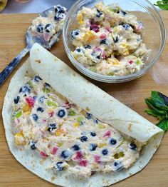 a tortilla filled with fruit salad next to a bowl of yogurt