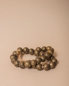 These brass African beads are beautifully textured, each individual bead unique in shape and finish for a final look that feels one-of-a-kind and natural. Perfect for layering on a vase, an open book, a bowl, or styling on a shelf. All Sales Final Free Shipping Bronze Brass Jewelry With Large Beads, Bronze Polished Round Bead Jewelry, Bronze Jewelry With Polished Round Beads, Bronze Jewelry With Large Beads, Artisan Brass Jewelry With Round Beads, Bronze Necklaces With Large Round Beads, Artisan Brass Jewelry With Large Beads, Artisan Gold Bracelets With Polished Beads, Gold Artisan Bracelet With Polished Beads