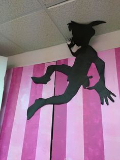 a paper cut out of a girl running on pink and white striped wall with black silhouette