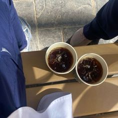 two cups filled with liquid sitting on top of a wooden table