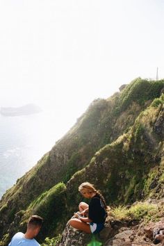 two people sitting on the edge of a cliff