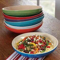 a bowl of pasta with tomatoes, olives, peppers and feta cheese on top