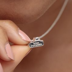 This vintage camera charm necklace is picture perfect, featuring all the assets of a classic srl camera with a single lens and flash detailing. Crafted from 925 sterling silver this three-dimensional camera pendant has been engraved with the words ‘stay focused’ on the bottom. An ideal gift for keen photographers or those who like to travel. This miniature camera adds a sense of adventure to your charm collection, bringing nostalgic memories of your best life without filters.  All our charms att Silver Vintage Charm Necklaces For Gifts, Silver Pendant Charm Necklace With Vintage Charm, Vintage Style Personalized Silver Charm Necklace, Sterling Silver Vintage Charm Necklace With Round Pendant, Sterling Silver Charm Necklace With Vintage Charm, Camera Pendant, Miniature Camera, Camera Charm, Camera Necklace