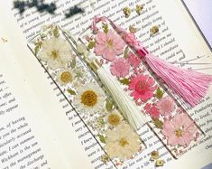 an open book with flowers and tassels on it