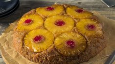 a pineapple upside down cake sitting on top of a piece of wax paper next to a knife