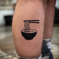 a black and white photo of a man's legs with chopsticks in a bowl