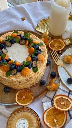 a cake with fruit on it sitting on top of a wooden table next to plates and utensils