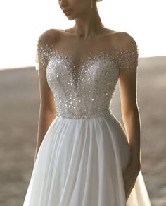 a woman in a white wedding dress with sequins on her shoulders and shoulder