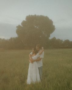 two people standing in a field hugging each other