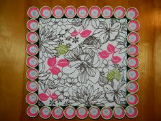 a pink and green flowered placemat on top of a wooden table next to a wall