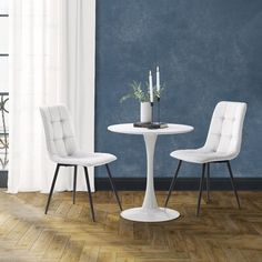 two white chairs and a table in a room with blue walls, hardwood floors and wooden flooring