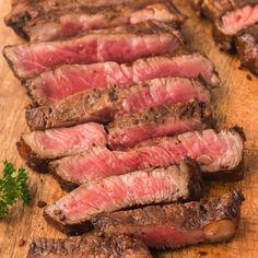 steak sliced up and ready to be served on a wooden cutting board with parsley