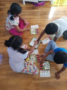 three children playing with matching cards on the floor