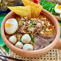 a bowl filled with meat and vegetables next to some tortilla chips on top of a table