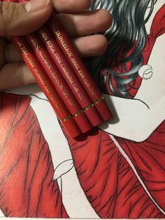 a person holding four red pencils in their hand