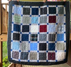 a woman holding up a quilt on top of a porch