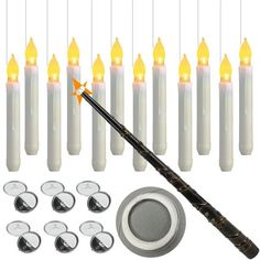 an assortment of white candles with orange lights on them and one black stick in the middle