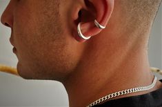 a close up of a man wearing a pair of silver hoop earrings on his ear