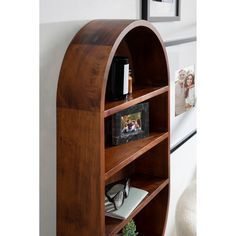 a wooden book shelf sitting next to a wall with pictures on the top and bottom shelves