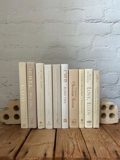 a row of books sitting on top of a wooden table next to a brick wall