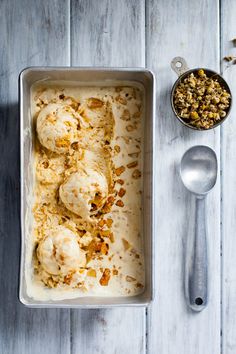 a pan filled with ice cream and toppings next to a bowl of granola