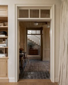 an open door leading to a living room with wooden furniture and bookshelves on either side