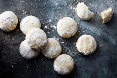 several doughnuts are on a black surface with powdered sugar scattered around them