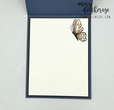 a white and blue card with a butterfly on the front, sitting next to it