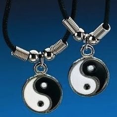 two black and white yin - yang pendants are hanging from a necklace on a cord