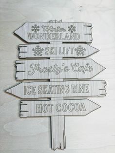 wooden signs pointing in different directions with snowflakes on them and the words wonderland, ski lift, frosty's cafe, ice skating rink, hot cocoa