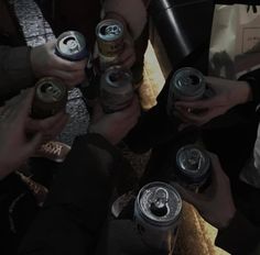 several people are holding cans of beer in their hands