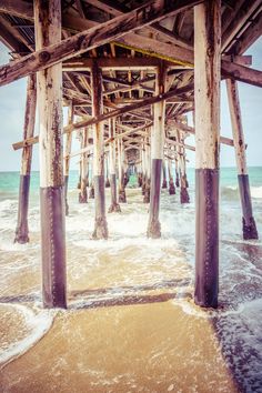 the underside of a pier with waves coming in